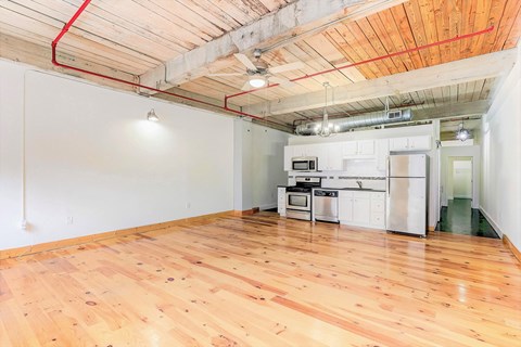 a kitchen and living room with hardwood floors and white walls